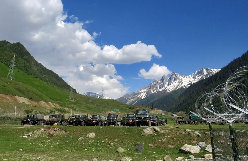 Indian army soldiers walk past their parked trucks at a makeshift transit camp before heading to Ladakh, near Baltal, southeast of Srinagar, June 16, 2020. REUTERS/Stringer